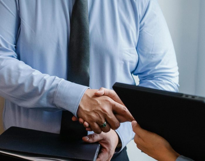 Business handshake between colleagues in a formal office meeting setting.