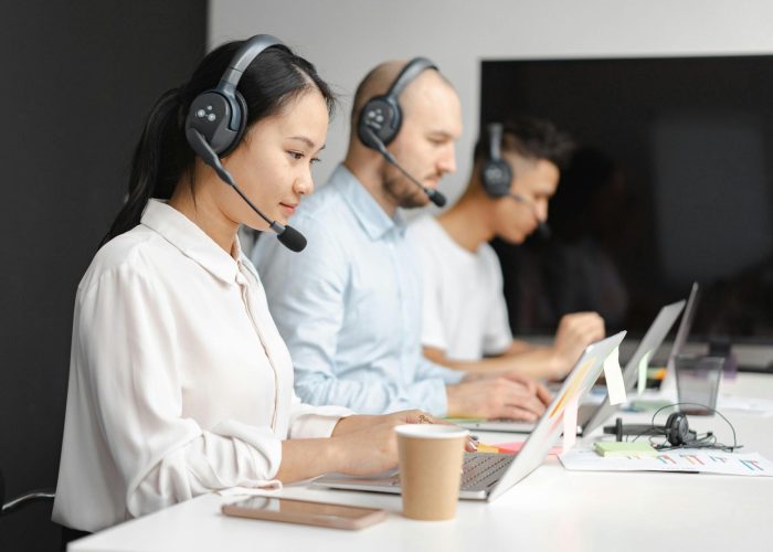 Customer service agents efficiently handle calls using laptops and headsets in a modern office.